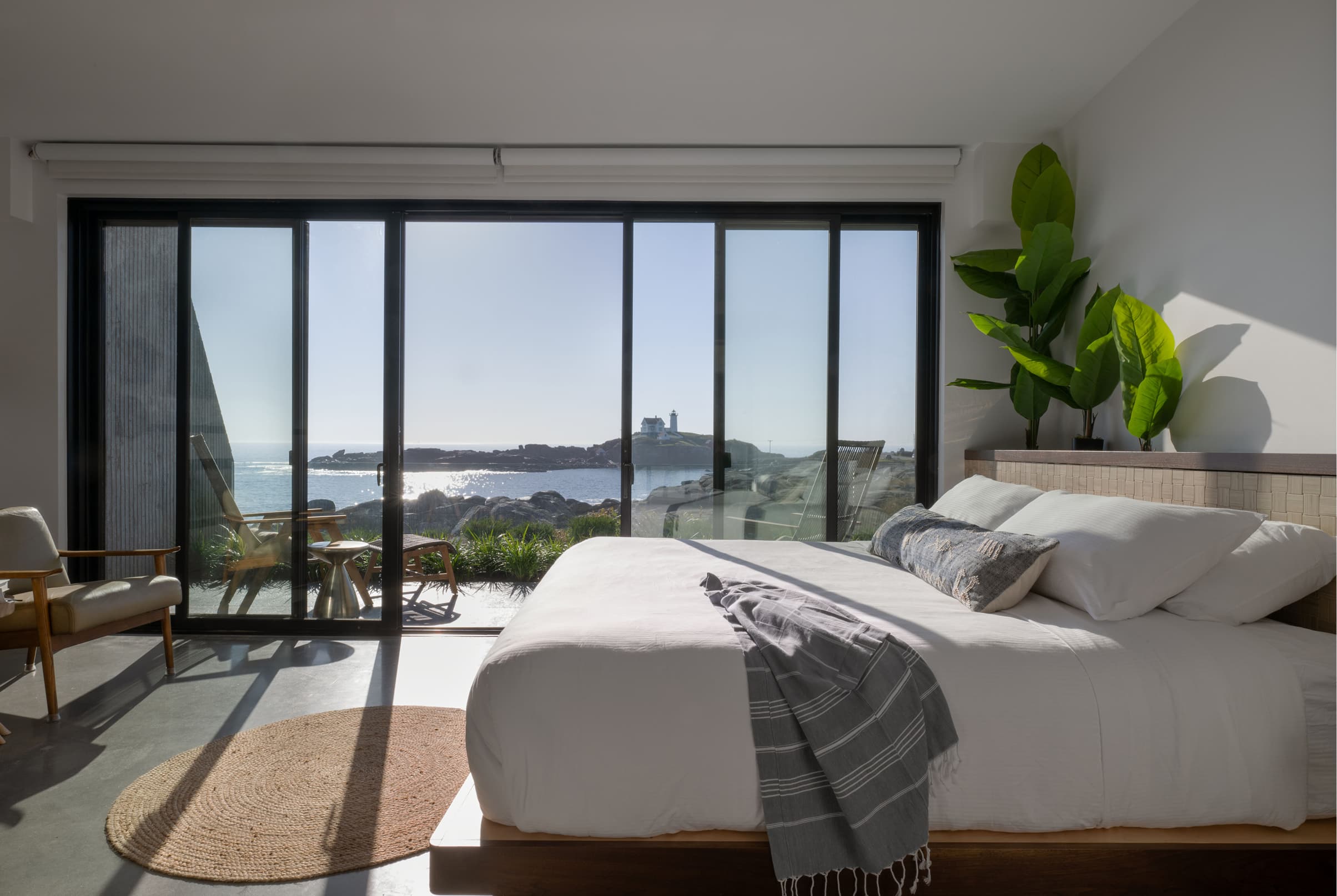 Bedroom interior with a large four-panel black Marvin Elevate Sliding Door looking out to water and a lighthouse.