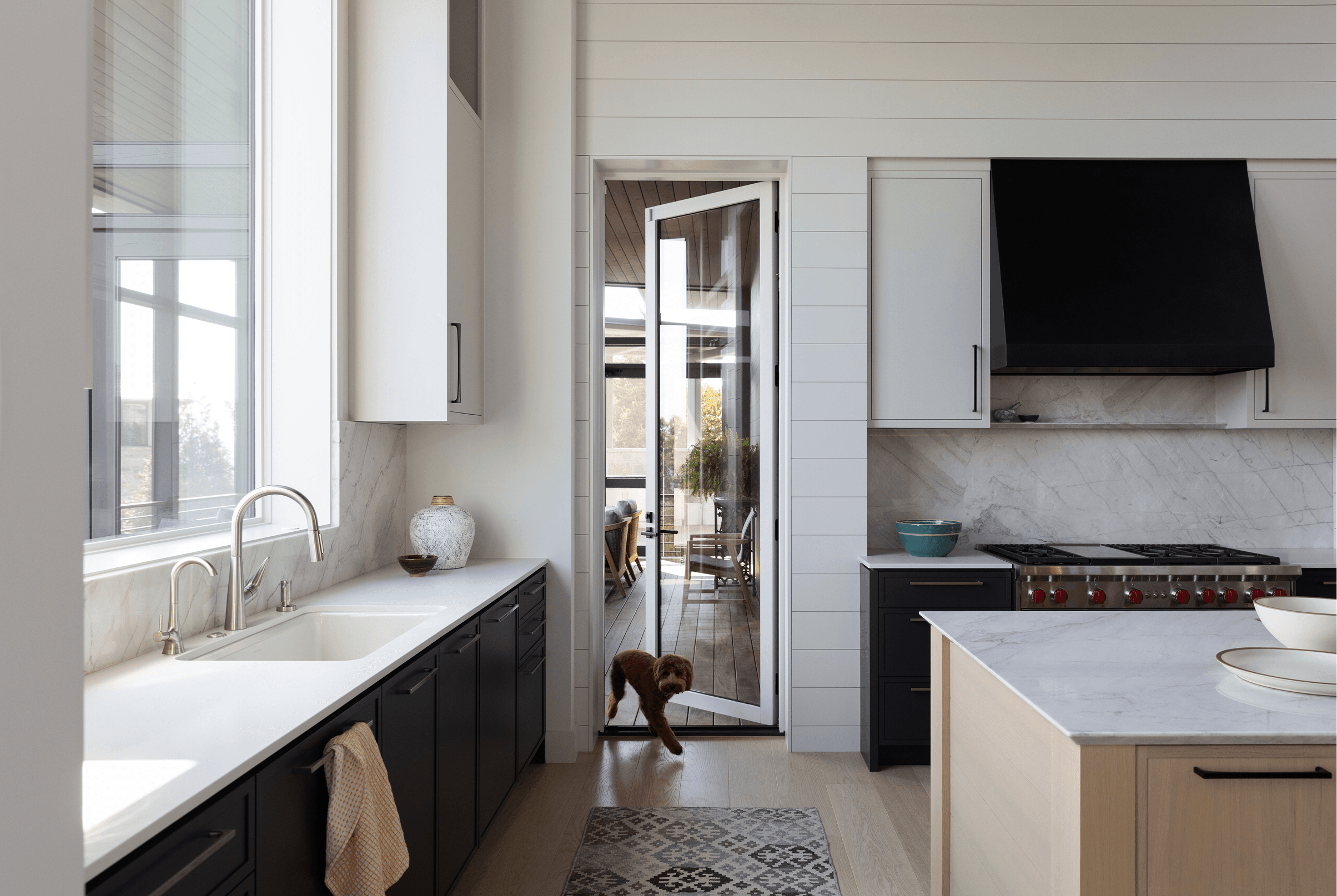 Kitchen interior with a dog walking through an opened white Marvin Ultimate Swinging Door.