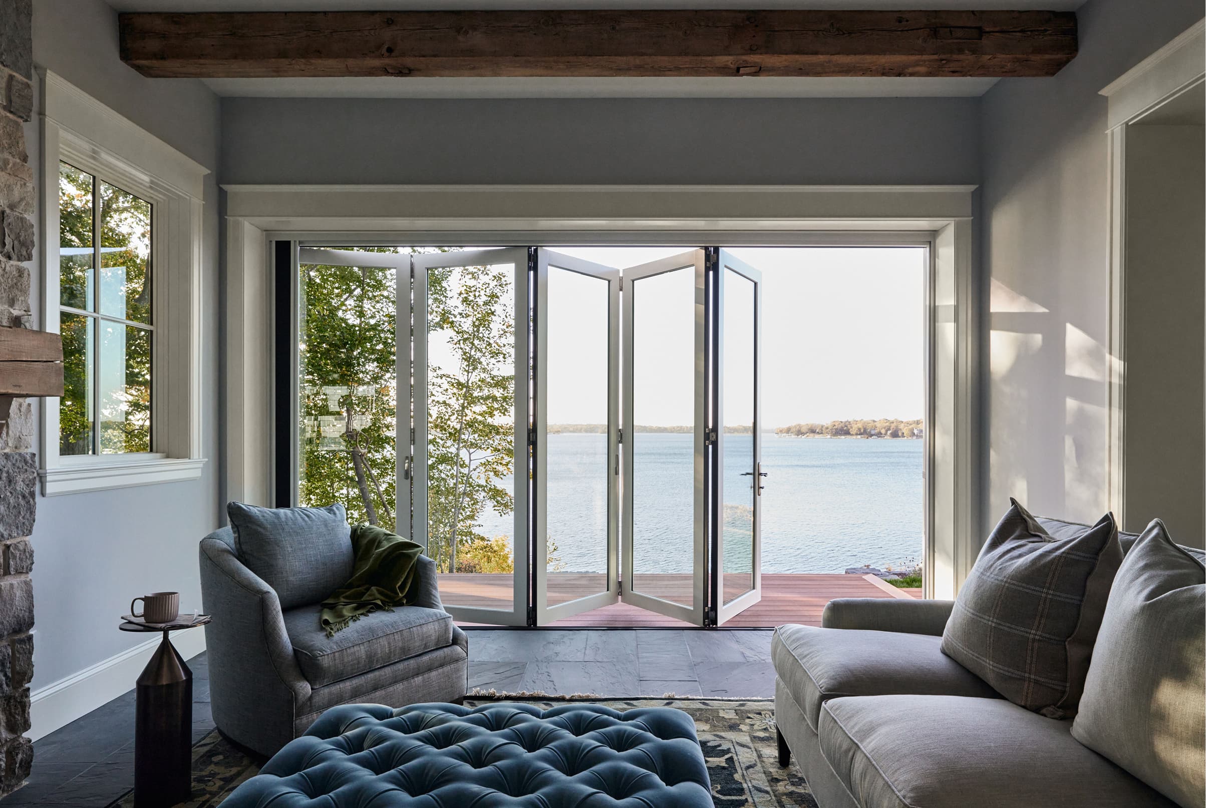 Living room interior showcasing an opened white five-panel Marvin Elevate Bi-Fold Door.