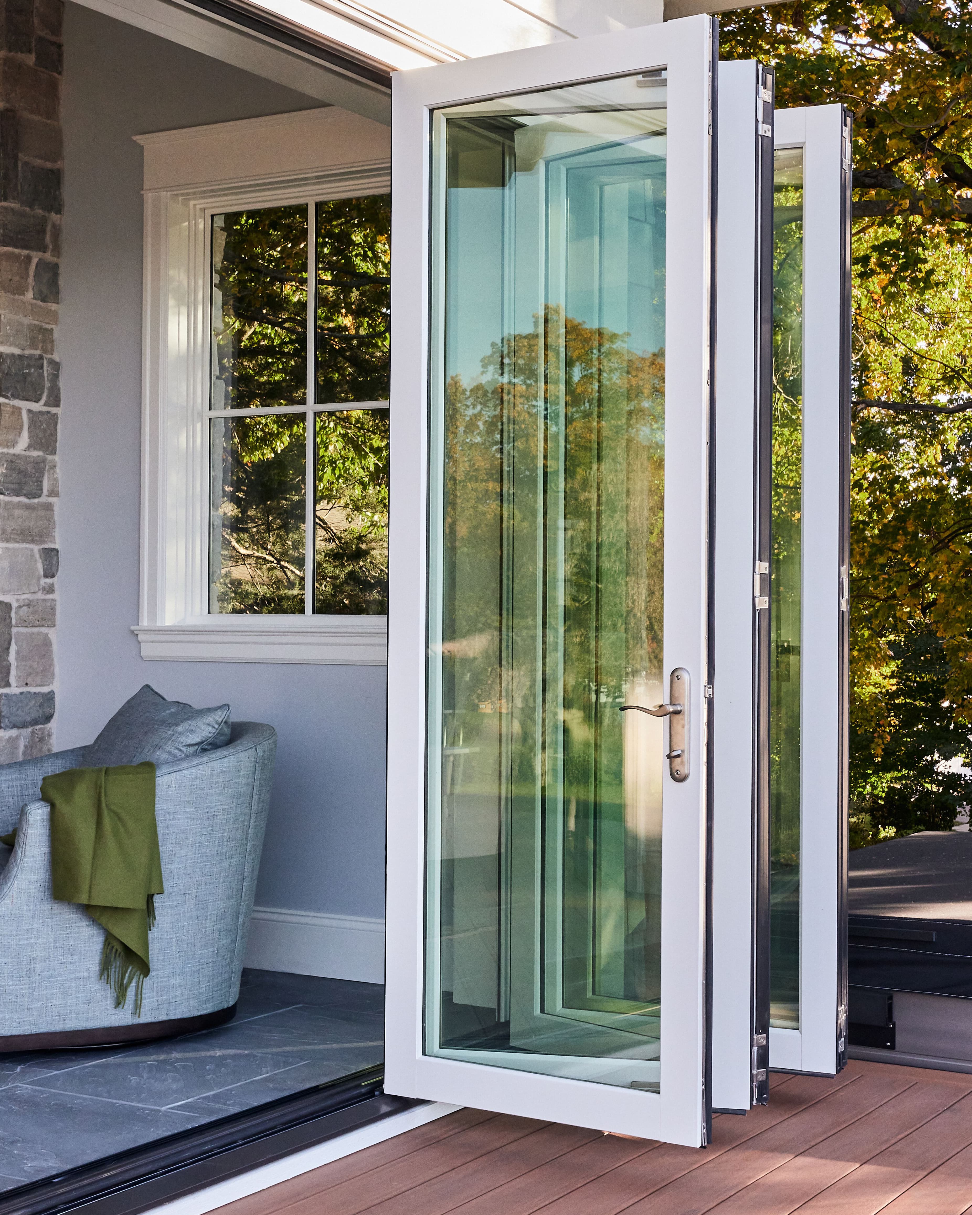 Home exterior from the deck showing an opened white Marvin Elevate Bi-Fold Door.