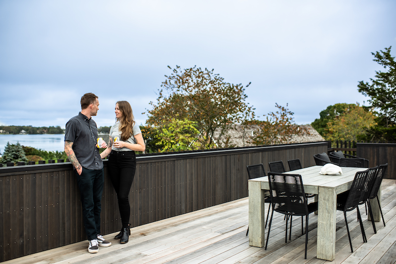 A man and woman standing on the deck of a modern home in Sag Harbor, New York, designed by THE UP STUDIO. 